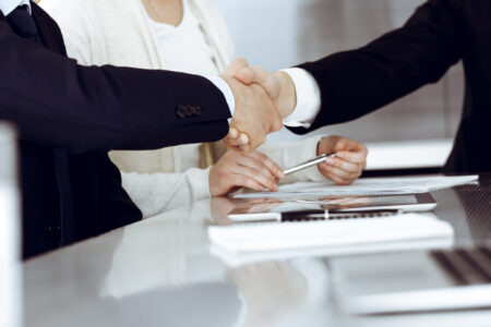 Business people shaking hands after contract signing in modern office. Teamwork, partnership and handshake concept.